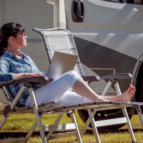 woman reclining with laptop in a chair outside