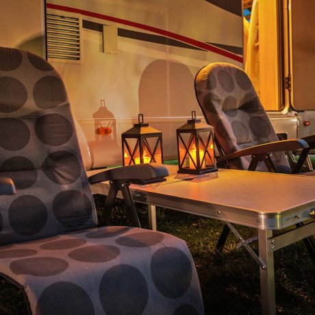 chairs outside an RV at night with lanterns